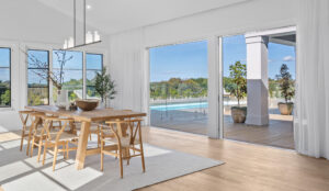 Light filled Hamptons living room, cased in premium steel windows, opening onto outdoor living through expansive sliding doors