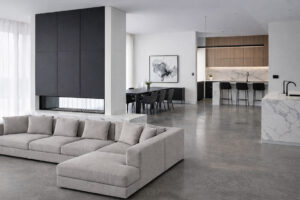 Spacious, open plan, modern contemporary living space, with floor to ceiling fire place, aluminium skirting and sealed concrete flooring