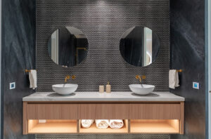 Modern bathroom, slate feature wall, round feature mirrors atop his and hers custom basins, set in a bespoke wooden floating vanity