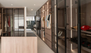 Walk through wardrobe with sleek, tinted glass doors, open shelving and hanging space, and a boutique island with glass display